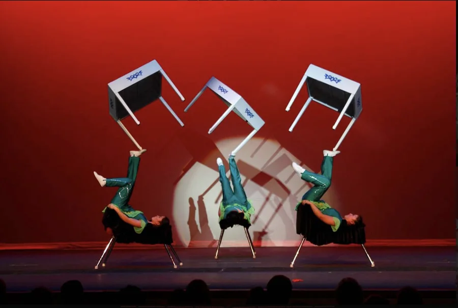 Chinese acrobats balancing on stacked chairs with tables on their feet