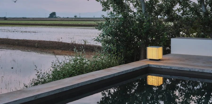 Shiro lamp by Antoni Arola, reflected in a pool at dusk